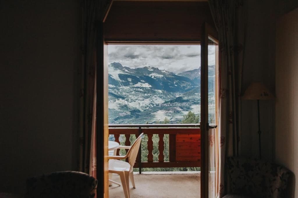 Una stanza con vista su montagne innevate attraverso una porta aperta.
