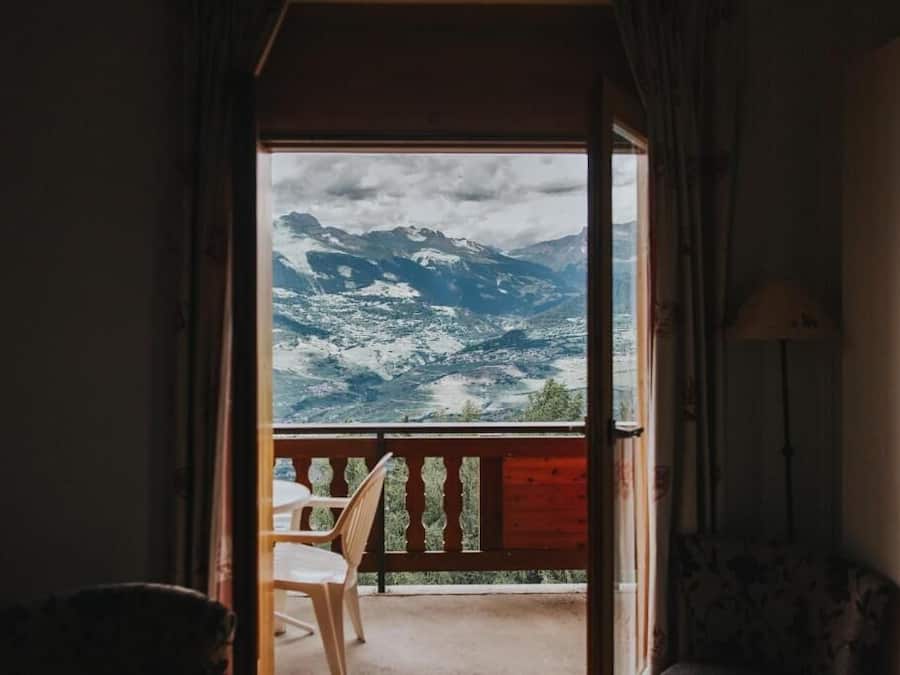 Una habitación con vistas a montañas nevadas a través de una puerta abierta.