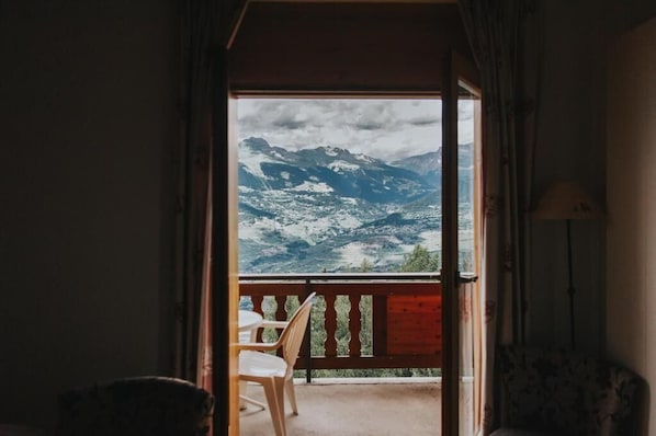 Una habitación con vistas a montañas nevadas a través de una puerta abierta.