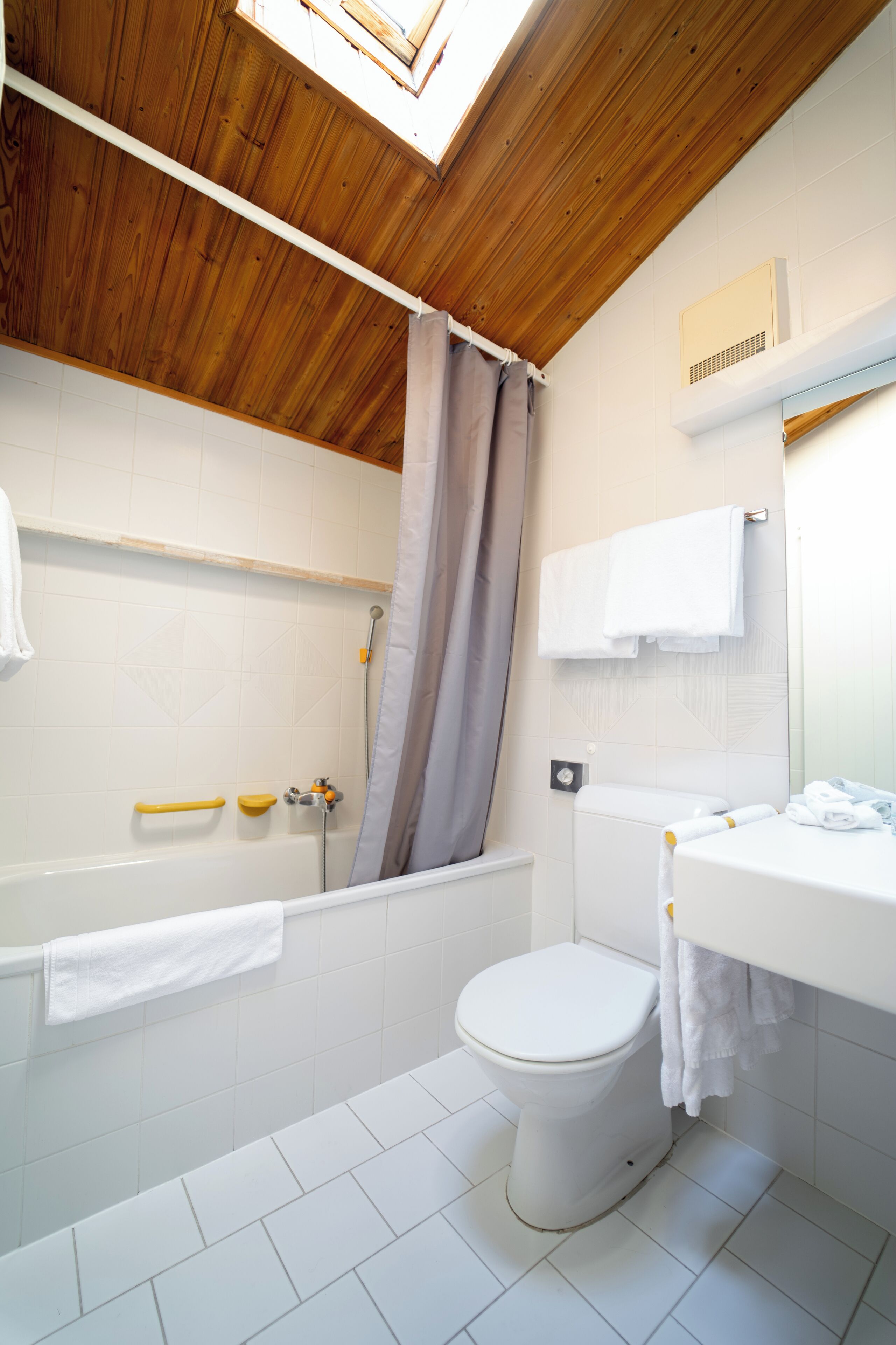 A bathroom with a wooden ceiling, a bathtub, a toilet, and a sink.