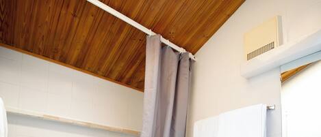 A bathroom with a wooden ceiling, a bathtub, a toilet, and a sink.