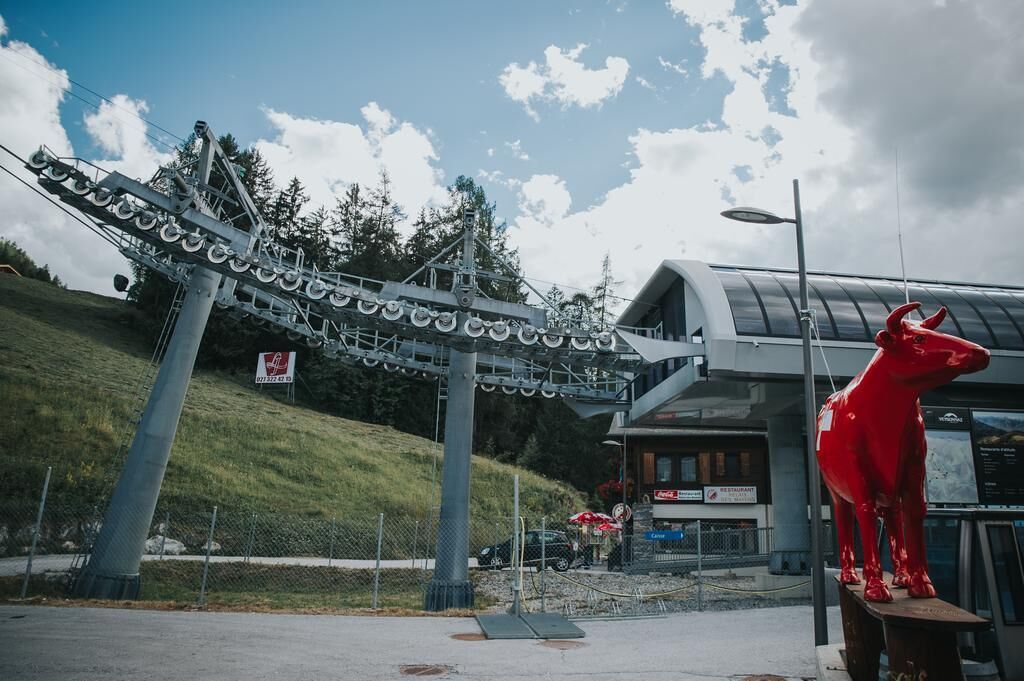 A ski lift structure, a red sculpture, and a building with a restaurant sign.