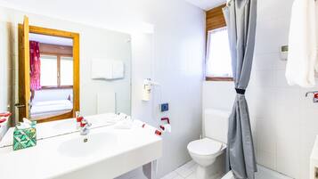 Une salle de bain avec un lavabo blanc, un miroir, des toilettes et un rideau de douche.