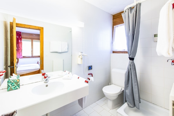 Un baño con lavamanos blanco, espejo, inodoro y cortina de ducha.