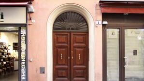 Una doble puerta de madera con un tragaluz encima, ubicada en un edificio de fachada color beige.