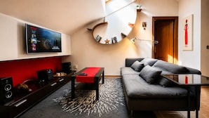 A modern living room with a TV, sofa, and a unique circular mirror. - Ático Centro Málaga (Málaga)