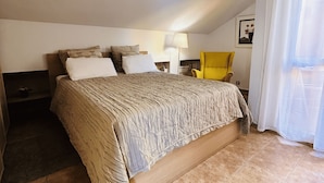 A bedroom with a large bed, a nightstand, a chair, and a lamp. - Ático Centro Málaga (Málaga)
