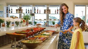 En buffet med forskelligt mad og en kvinde, der serverer et barn.
