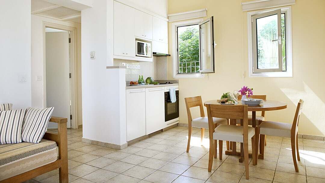 A compact kitchen with white cabinets, a microwave, and a dining area with a wooden table and chairs.