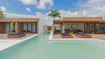 Relax by the rectangular pool surrounded by lounge chairs and wooden deck flooring.