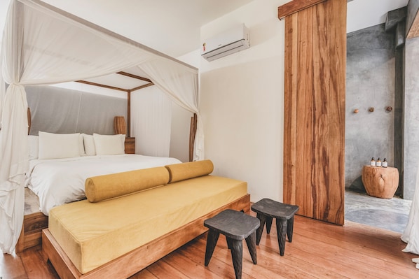 Une chambre à coucher avec un lit à baldaquin, un plancher en bois, un banc et une petite table.