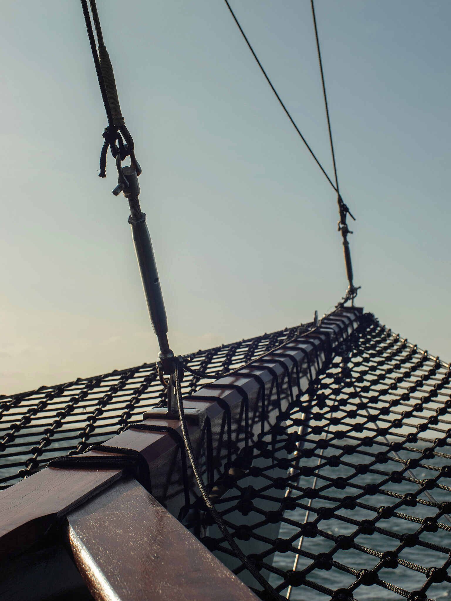 A close-up of a ship's netting and rigging, with a clear sky in the background.