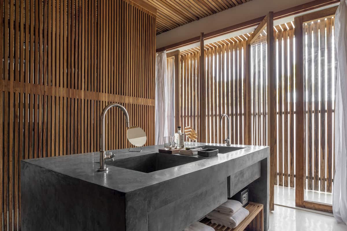Un baño moderno con un lavamanos grande, listones de madera y vistas a través de una ventana.