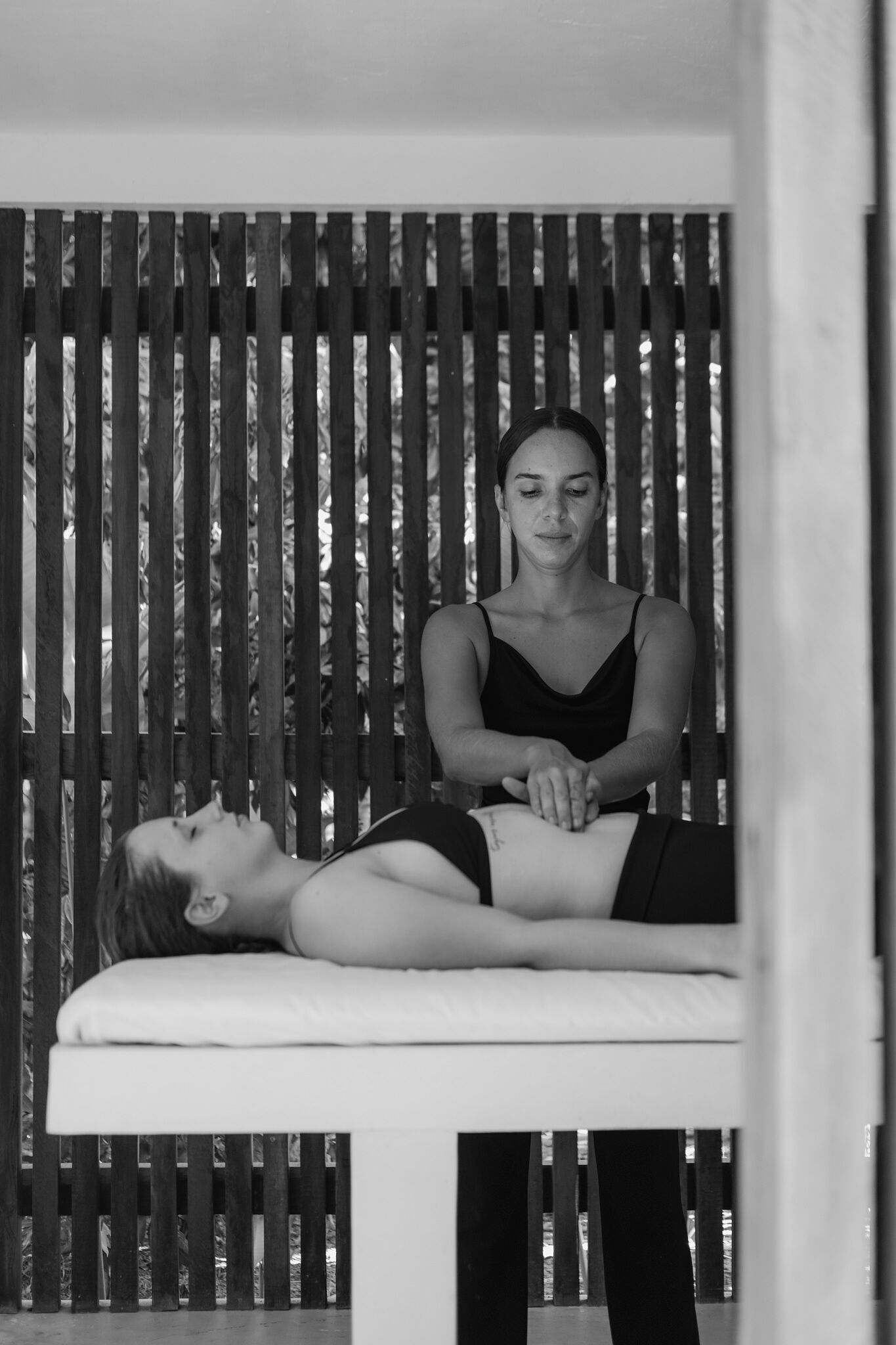 A person lying on a massage table receiving a back massage.