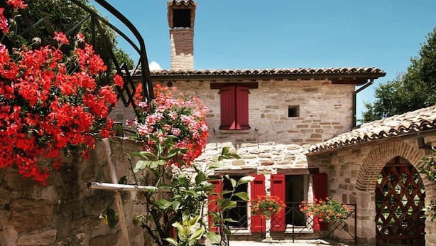 A stone building with red shutters and a chimney. - Fonte al Noce (Gubbio)