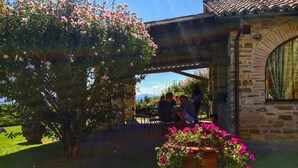 An outdoor patio area with stone walls, a pergola, and a table with chairs. - Fonte al Noce (Gubbio)