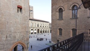 A courtyard with a large open space, a historic building with arched windows, and a metal railing. - Casa Isolani Piazza Maggiore (Bologna)