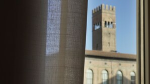 A view of a building with a tall tower and arched windows. - Casa Isolani Piazza Maggiore (Bologna)