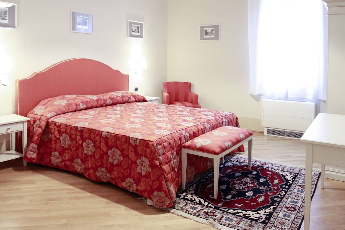 Un dormitorio con una cama, una silla, un escritorio y una ventana.
