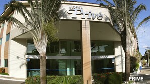 Un hotel llamado 'PRIVATE' con una fachada moderna, amplios ventanales y palmeras al frente.