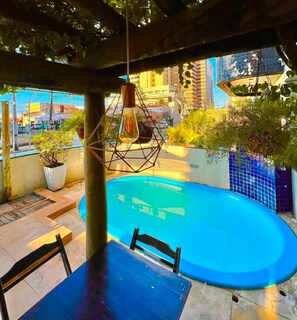 A rooftop pool area with a blue pool, a hanging light fixture, and potted plants. - Ara Mar Praia Hotel (Fortaleza)