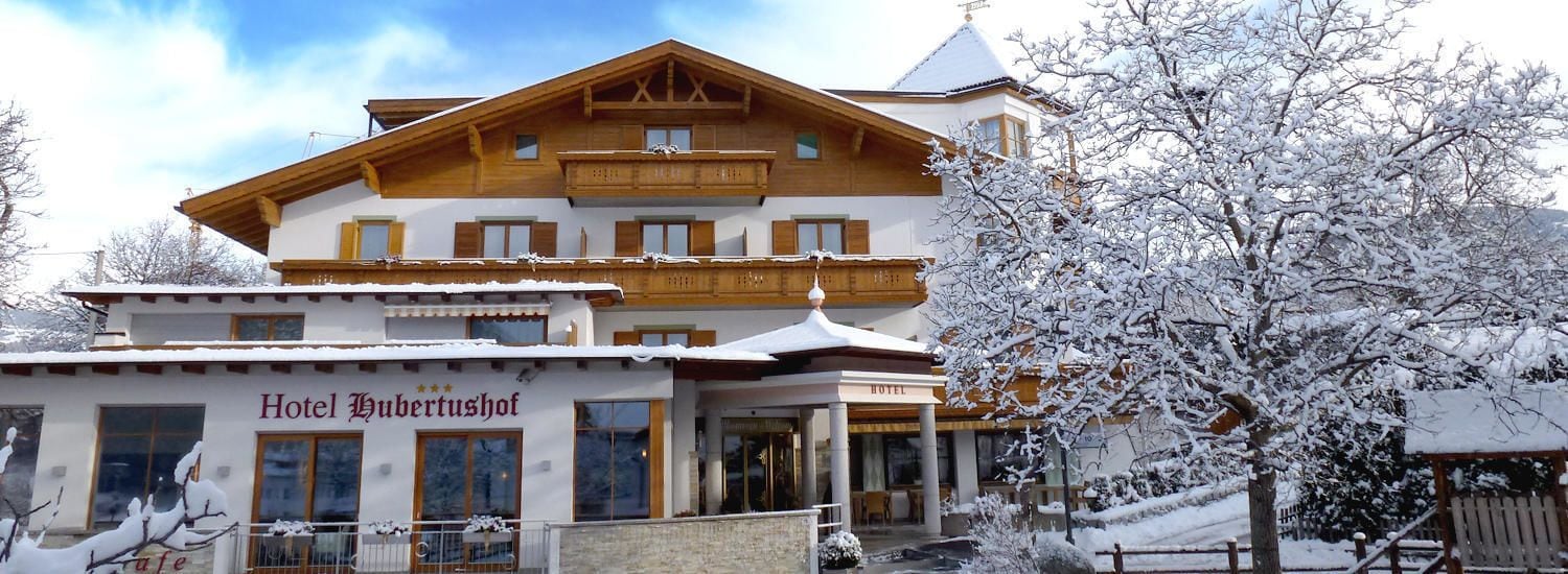 Un hotel di due piani in stile architettonico alpino tradizionale, con balconi in legno e un paesaggio innevato.