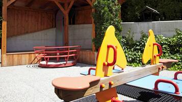 Un patio de juegos al aire libre con balancines y una estructura roja.