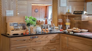 A wooden kitchen with a built-in coffee machine, a fruit bowl, and various kitchen utensils. - Hotel Hubertushof (Naz Sciaves)