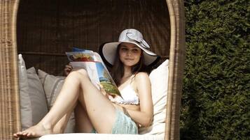 Une personne assise dans un fauteuil en osier, en train de lire un magazine.