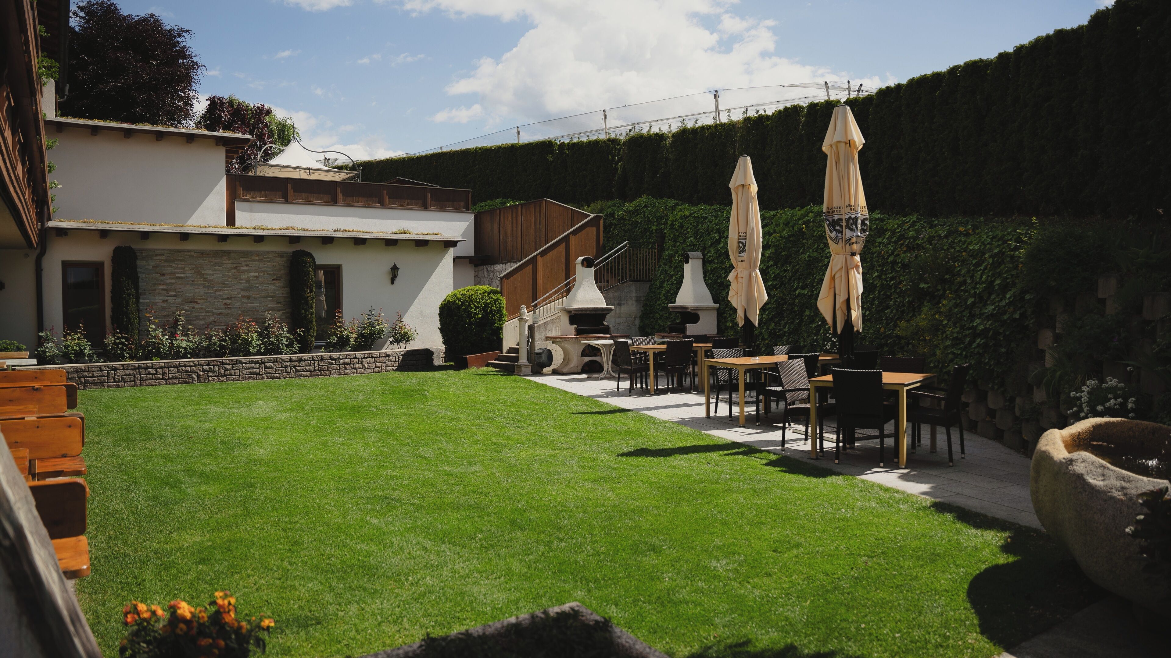 A well-maintained outdoor patio area with a lawn, outdoor seating, and a stone wall.