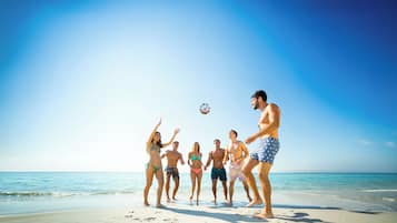A group of people playing soccer on a beach.