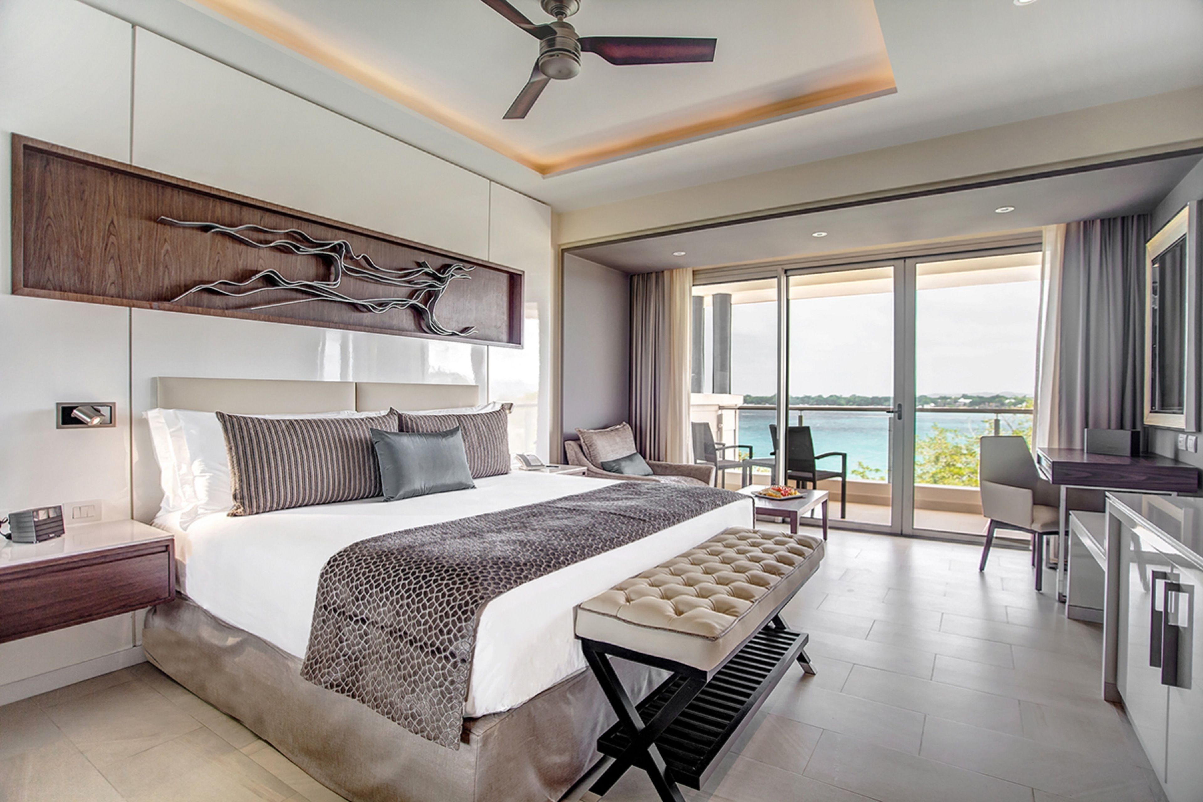 Un hotel moderno con una cama grande, un escritorio y vistas al mar.