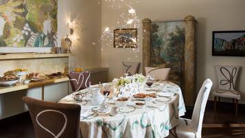 Un coin repas avec une table mise pour le repas, entourée de chaises, un tableau au mur et un luminaire décoratif.