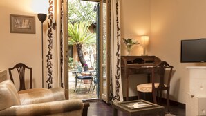 A room with a sofa, a small table, a desk with a chair, a lamp, and a television. - Buonanotte Garibaldi (Rome)