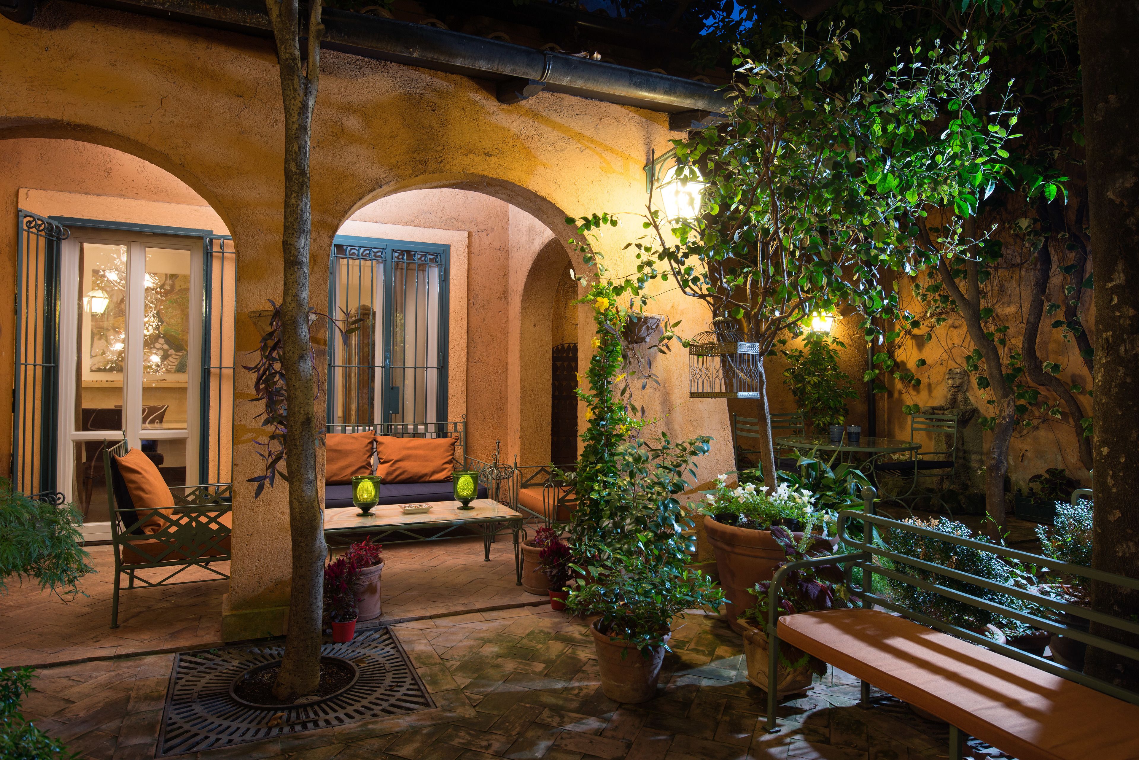 An outdoor patio area with a bench, potted plants, and a stone floor.