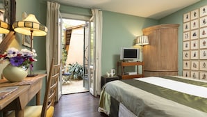 A bedroom with a bed, a desk with a lamp, a television, and a wall with framed pictures. - Buonanotte Garibaldi (Rome)