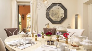 A dining table set with white tableware, a mirror, and decorative flowers. - Buonanotte Garibaldi (Rome)