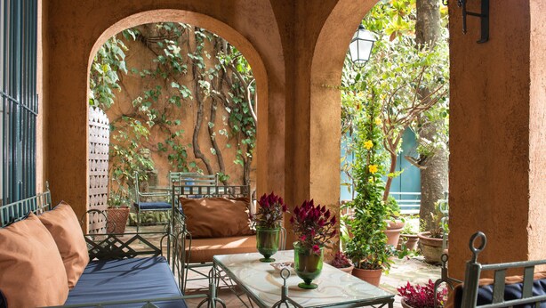 An outdoor patio with a table and chairs, surrounded by arches and potted plants. - Buonanotte Garibaldi (Rome)