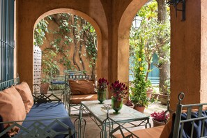Eine Außenpatio mit Tisch und Stühlen, umgeben von Bögen und Topfpflanzen.