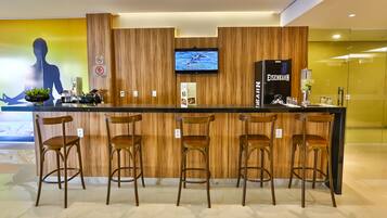 A bar area with wooden paneling, a television mounted above the bar, and a refrigerator labeled "Eisenbahn".