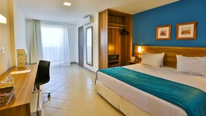 A hotel room with a bed, a desk with a chair, a wardrobe, a bedside table with a lamp, and a window with curtains. - Arcus Hotel Aracaju by Atlantica (Aracaju)