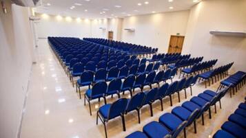 Un salón de conferencias con filas de sillas azules y un suelo pulido.