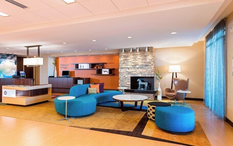 A modern lobby with a reception desk, seating area, and a stone fireplace.
