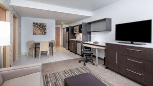 A modern hotel room with a dining area, kitchenette, and a large flat-screen TV. - Home2 Suites by Hilton Ft. Lauderdale Airport-Cruise Port (Dania Beach)