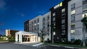 A modern hotel with a prominent "HOME 2" sign, a covered entrance, and a parking area with handicapped accessibility. - Home2 Suites by Hilton Ft. Lauderdale Airport-Cruise Port (Dania Beach)
