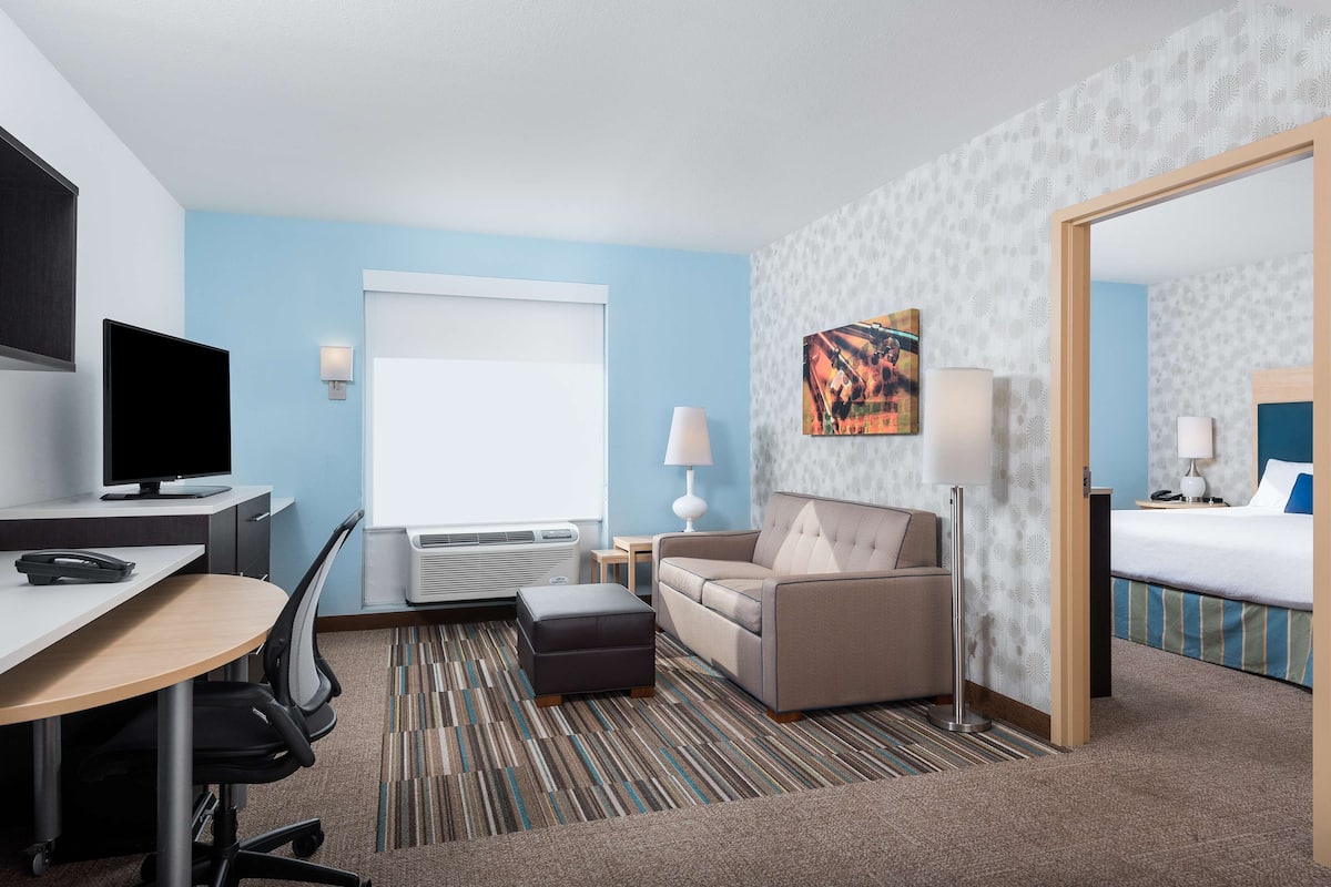 A hotel room with a desk, chair, sofa, and a bed.