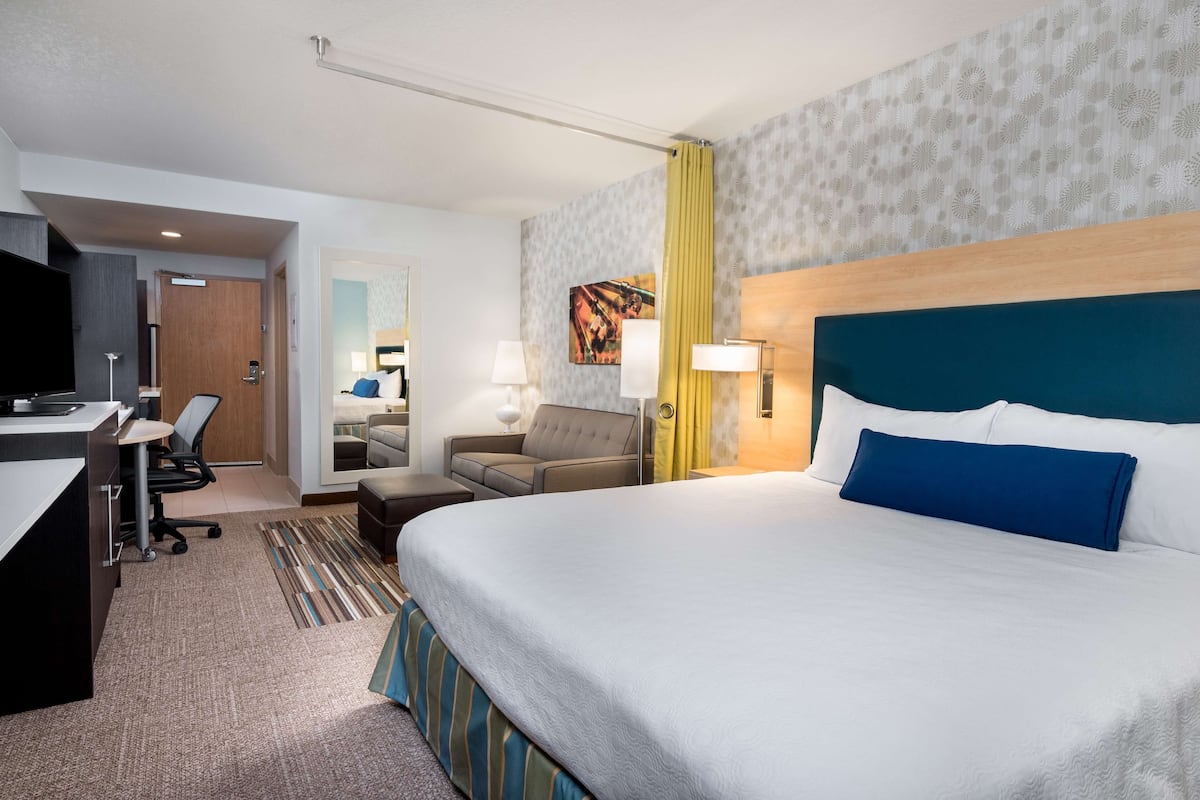 A hotel room with a bed, desk, chair, and a television.