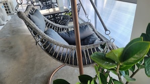 A wicker chair with cushions, a potted plant, and a concrete floor. - Luichy's Seaside Hotel (Cabo Rojo)