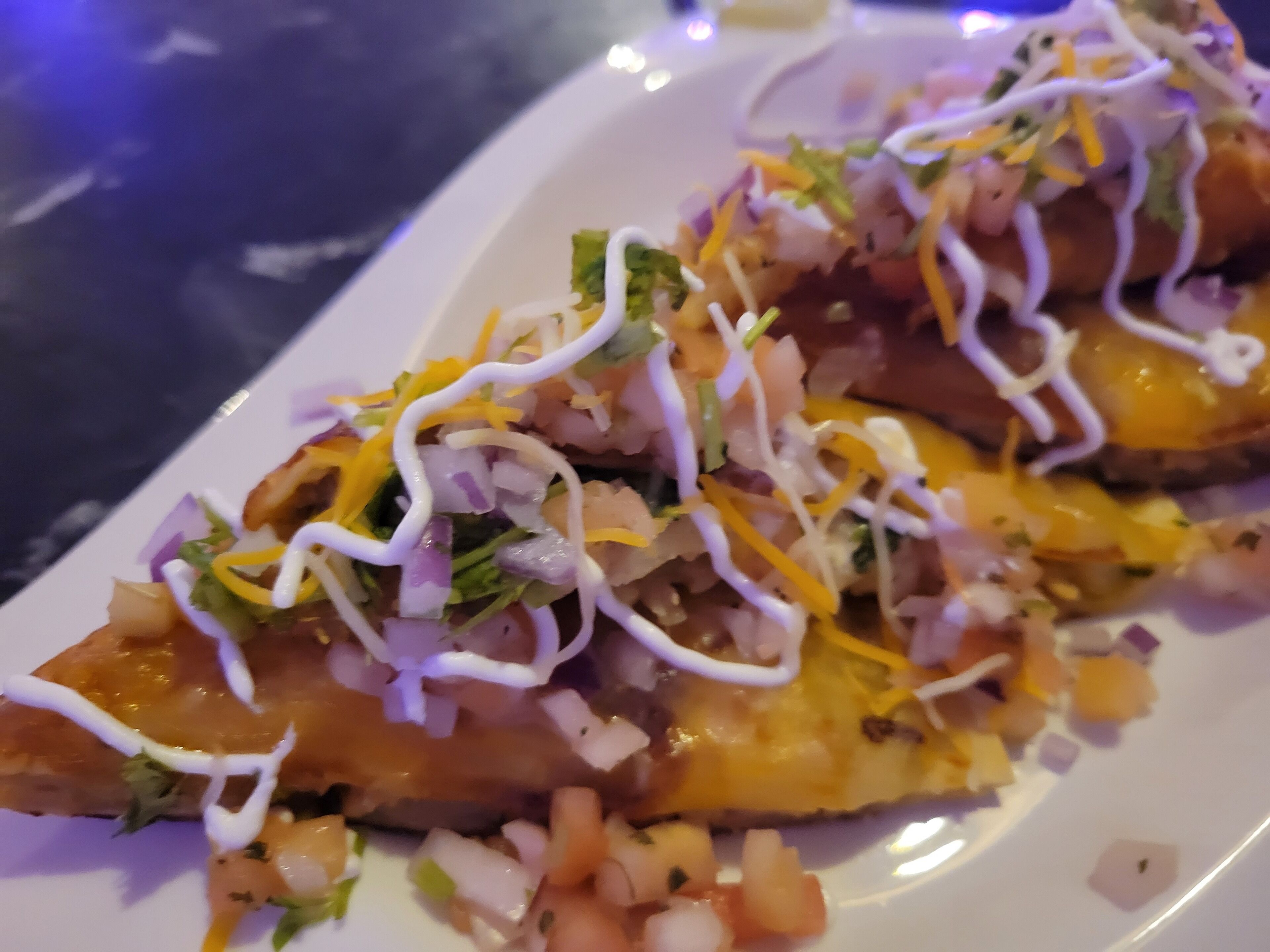 A plate of nachos topped with cheese, sour cream, and various toppings.