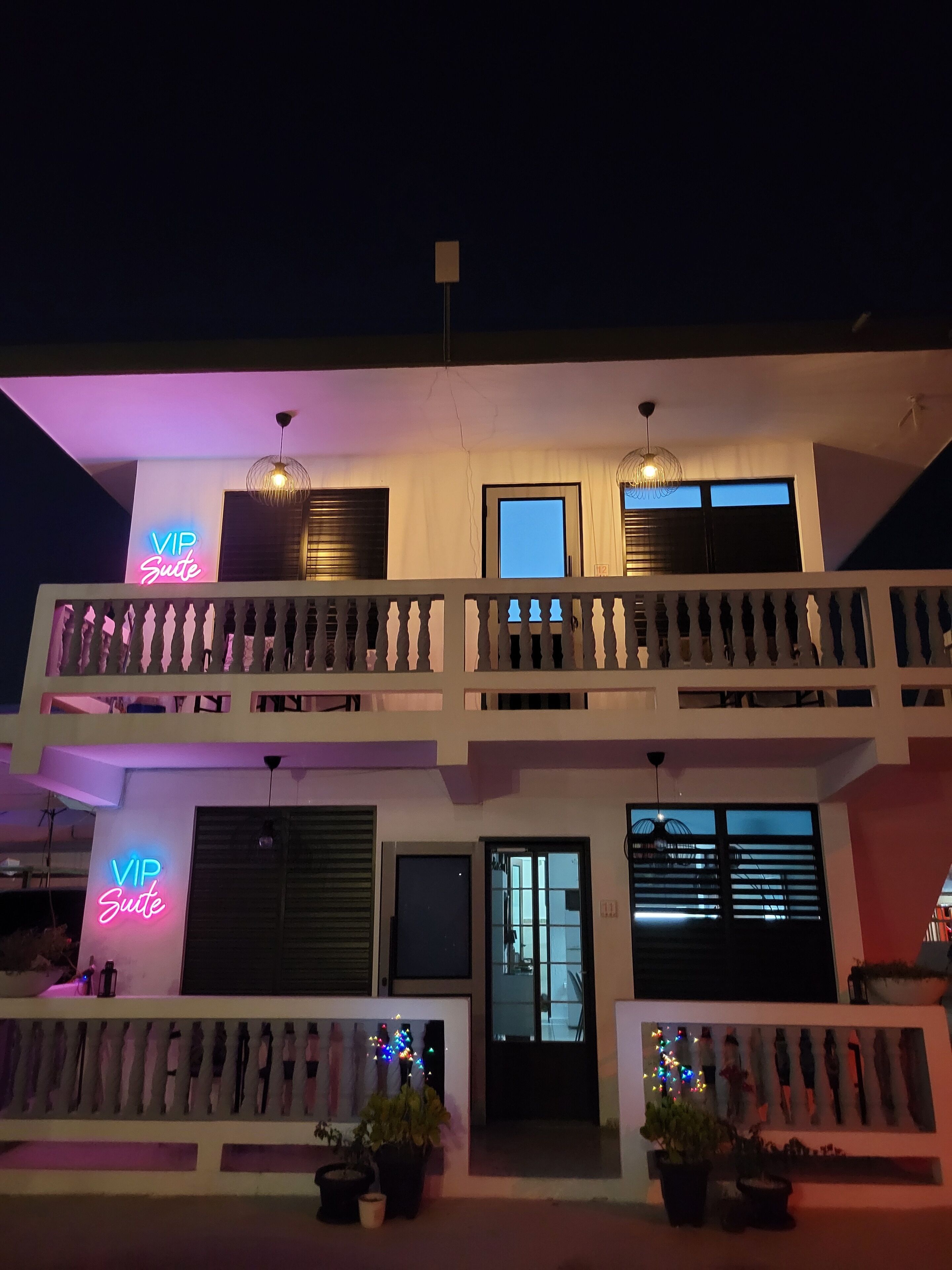 A two-story building with a balcony, a neon sign reading "VIP Suite," and a door with a window.